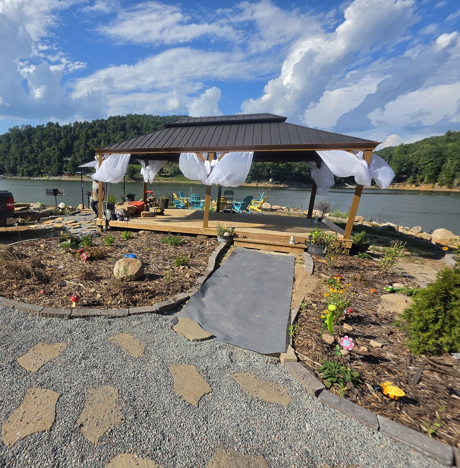 The covered pavilion with white curtains beside the lake under summer clouds