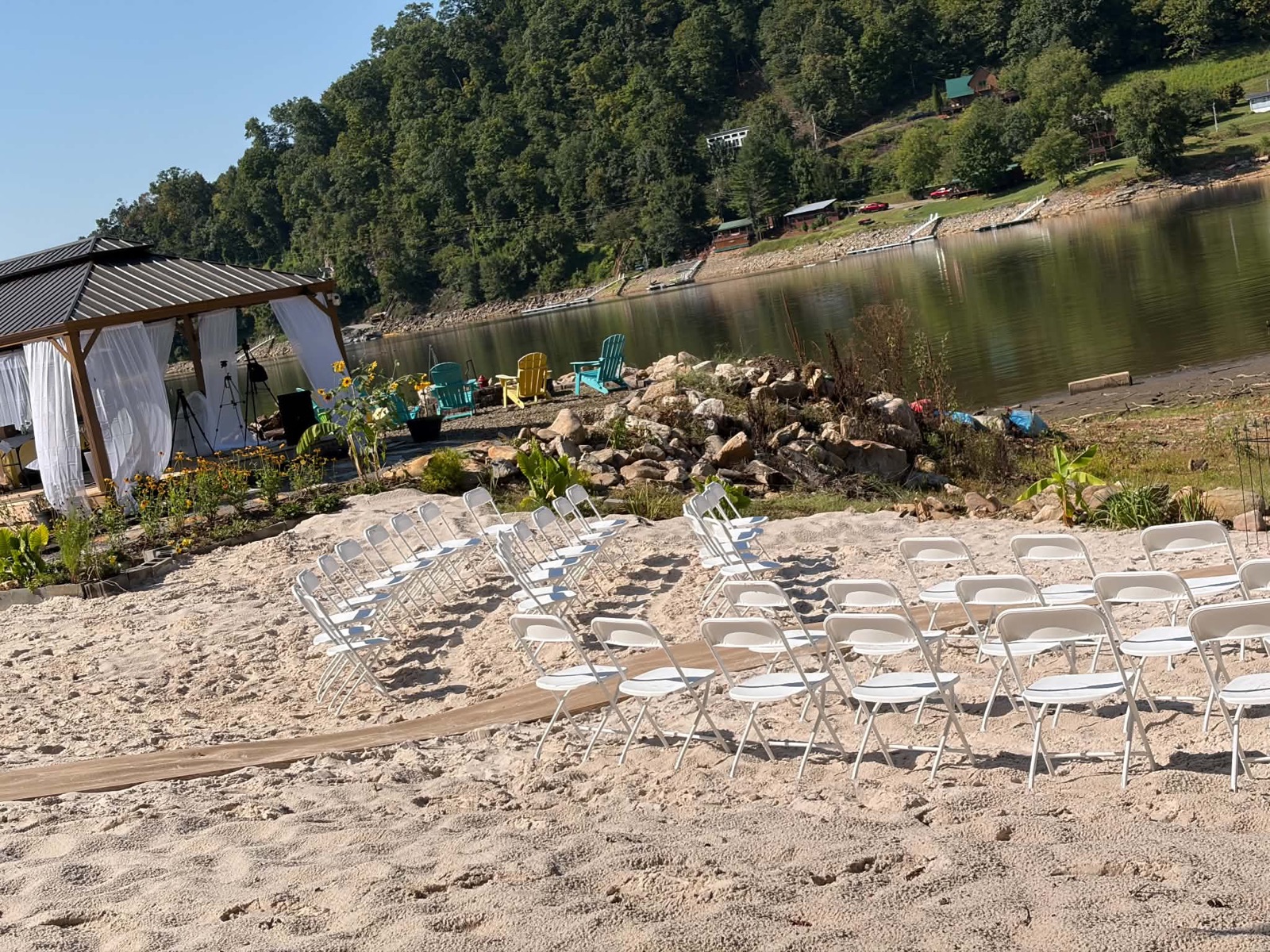 White-sand beach set for a wedding ceremony beside the pavilion and lake