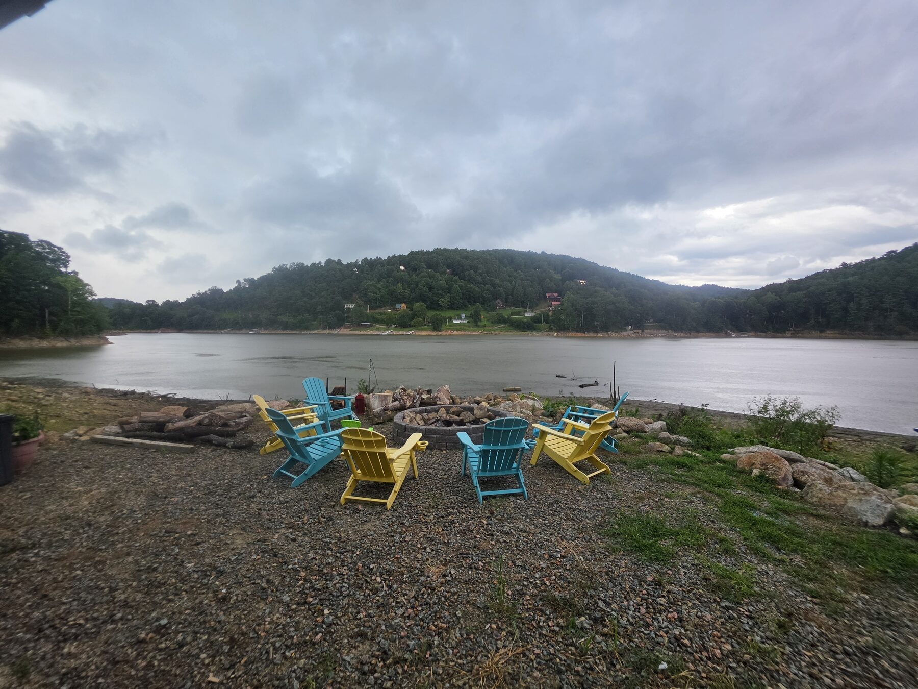 Circle of Adirondack chairs around the stone fire pit on the beach