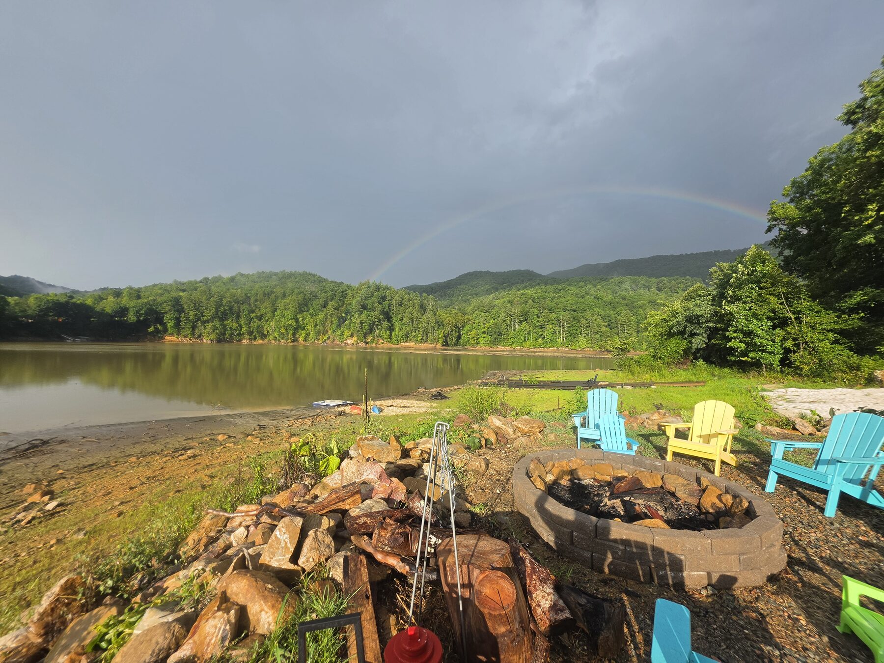 Rainbow over the lakeside fire pit and colorful Adirondack chairs