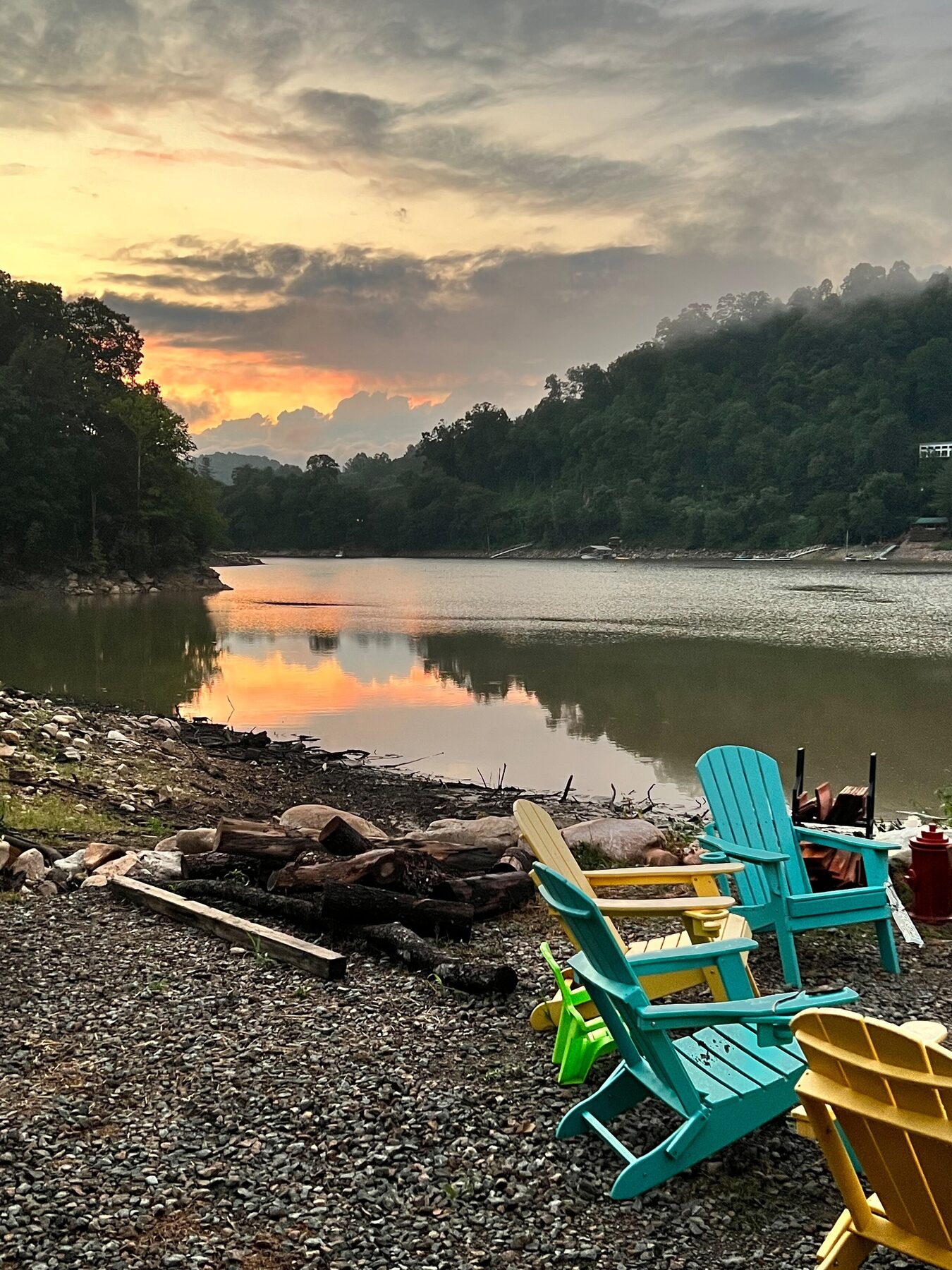 Adirondack chairs by the fire pit at sunset on the lake shore